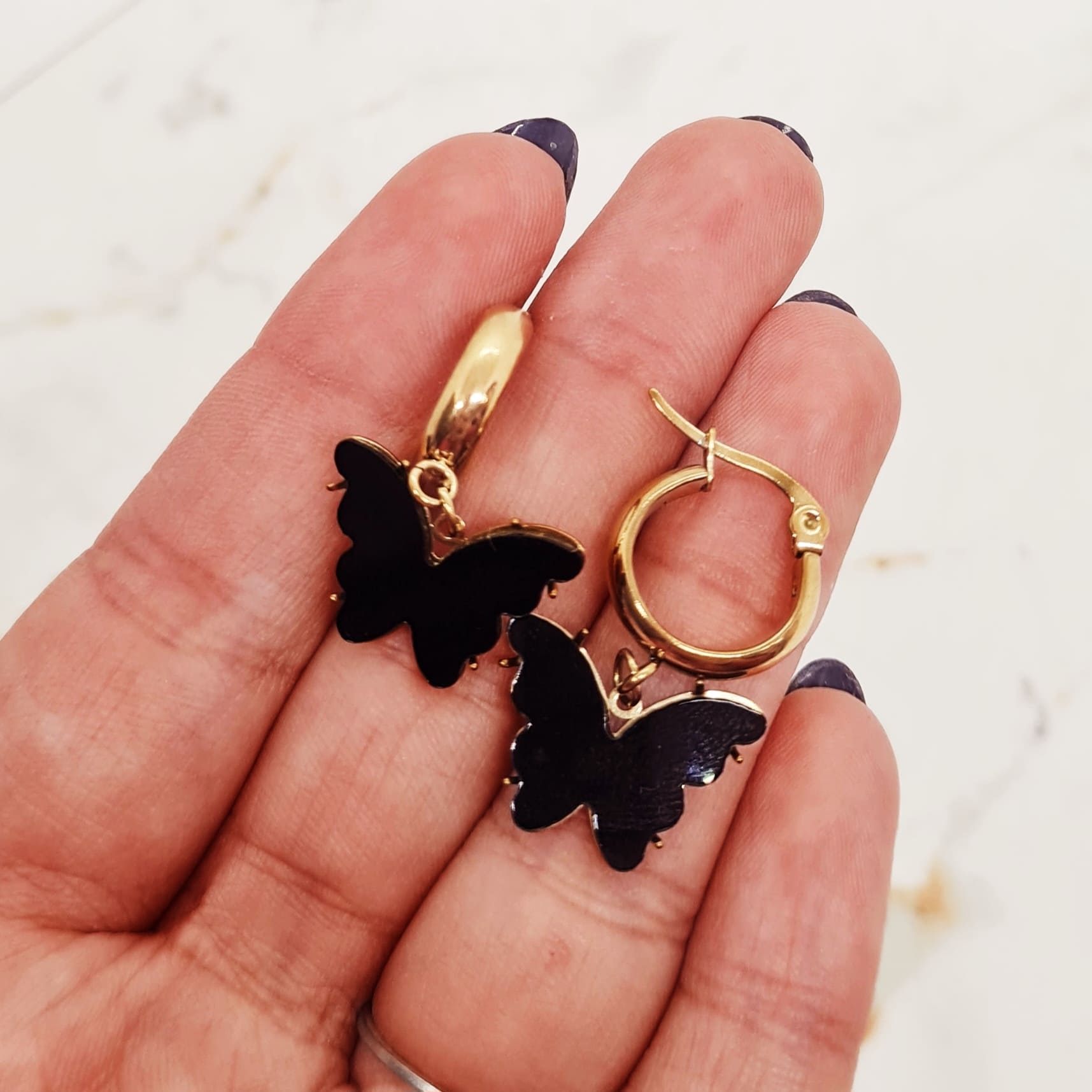 Imagen de producto ARGOLLA ACERO DORADO ANCHA CON MARIPOSA - NEGRA