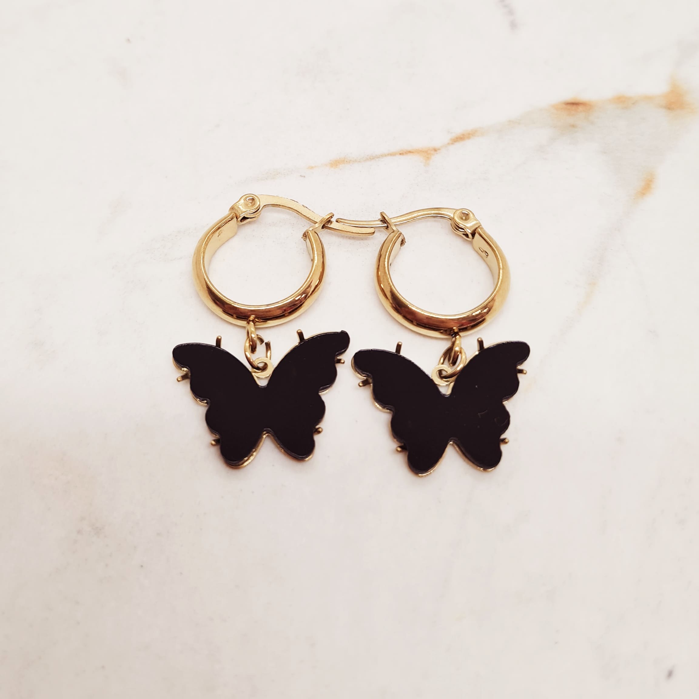 Imagen de producto ARGOLLA ACERO DORADO ANCHA CON MARIPOSA - NEGRA