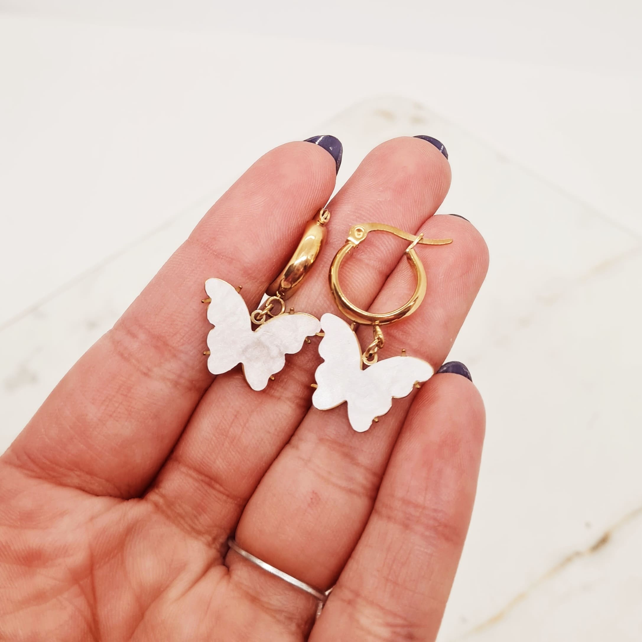 Imagen de producto ARGOLLA ACERO DORADO ANCHA CON MARIPOSA - BLANCA